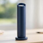 Dyson HushJet Mini Cool bladeless personal fan in dark blue standing on its charging dock on a bright desk